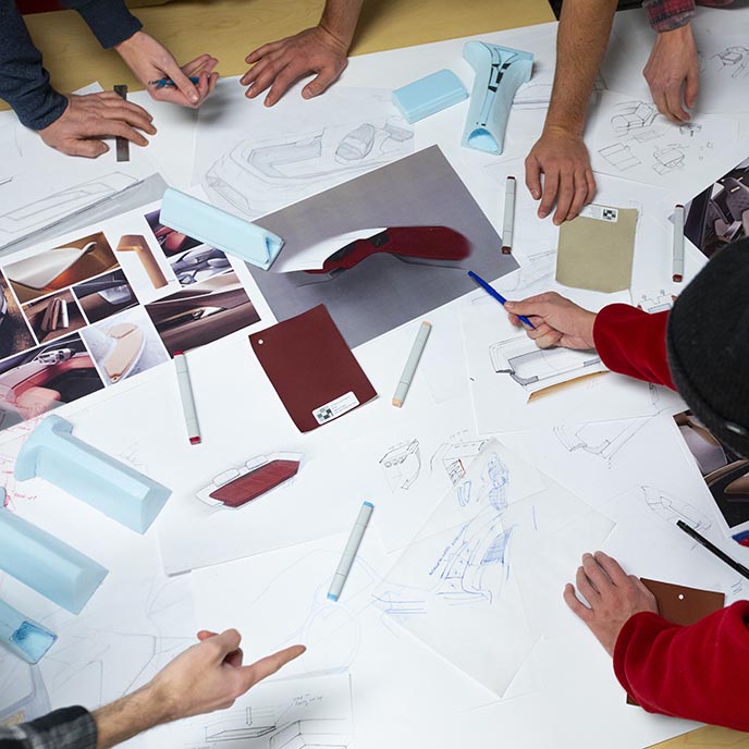 Closeup view of the hands of several people doing planning and design work.